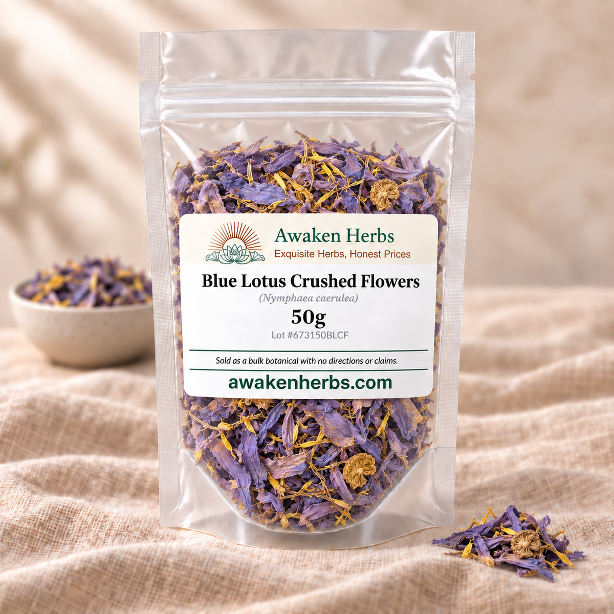 Blue Lotus Crushed Flowers 50g in a clear Awaken Herbs stand-up pouch on beige linen, with a softly blurred bowl and one small product cluster.