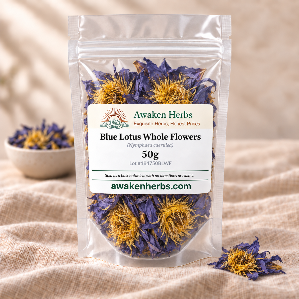 Blue Lotus Whole Flowers 50g in a clear Awaken Herbs stand-up pouch on beige linen, with a softly blurred bowl and one small product cluster.